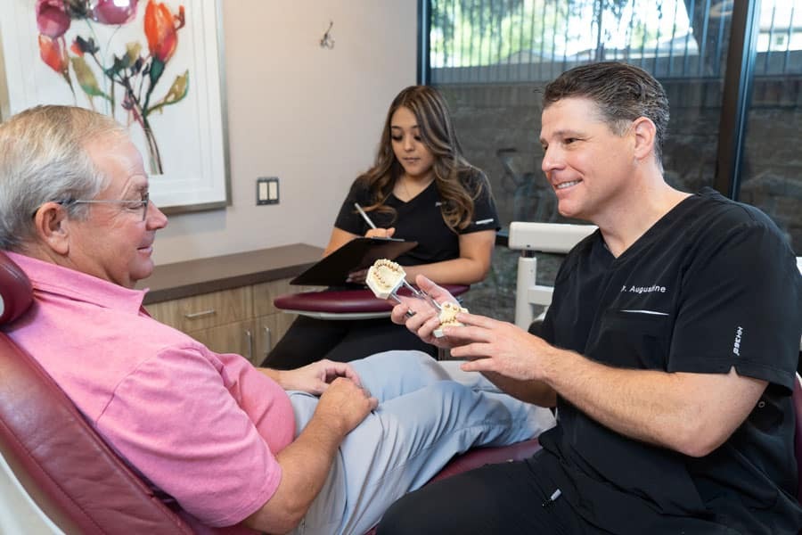 Periodontist showing dental model to patient during consultation in Phoenix dental office.
