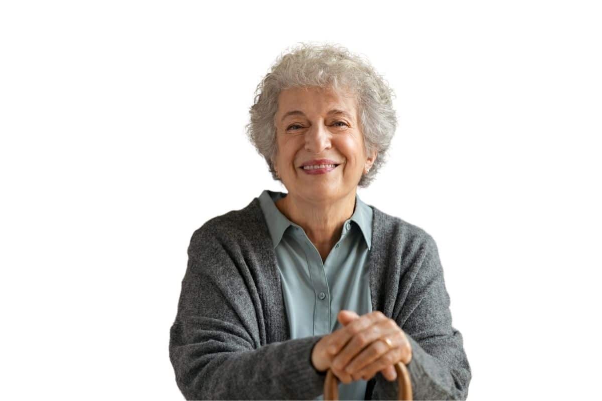 Smiling senior woman with gray hair wearing a cardigan and light blue shirt.