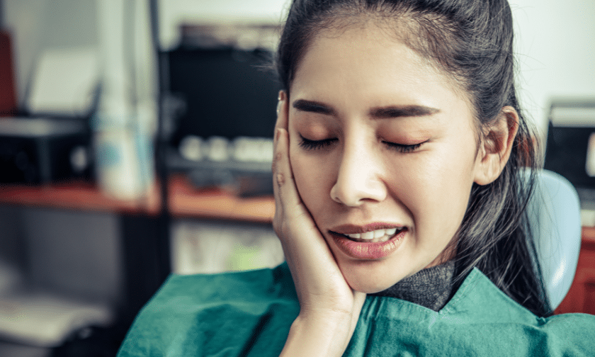 Gum Disease Treatment Woman experiencing tooth pain, holding her cheek in discomfort during gum disease treatment consultation.