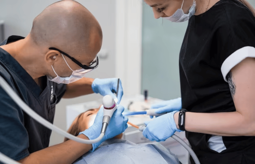 Dentist performing crown lengthening procedure on patient with dental handpiece in Phoenix office.