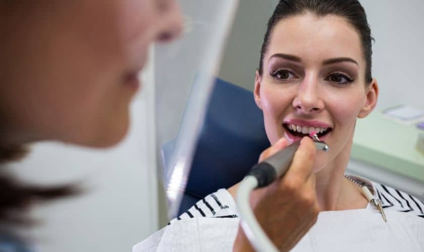 Woman examining her smile during dental consultation with dentist in Phoenix.