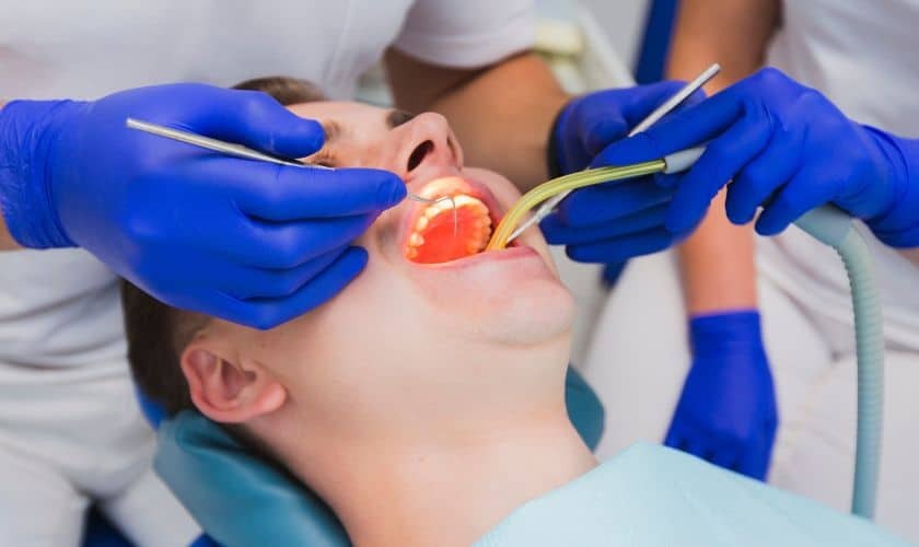 Osseous Surgery Dentist performing osseous surgery on patient's gums using surgical instruments.