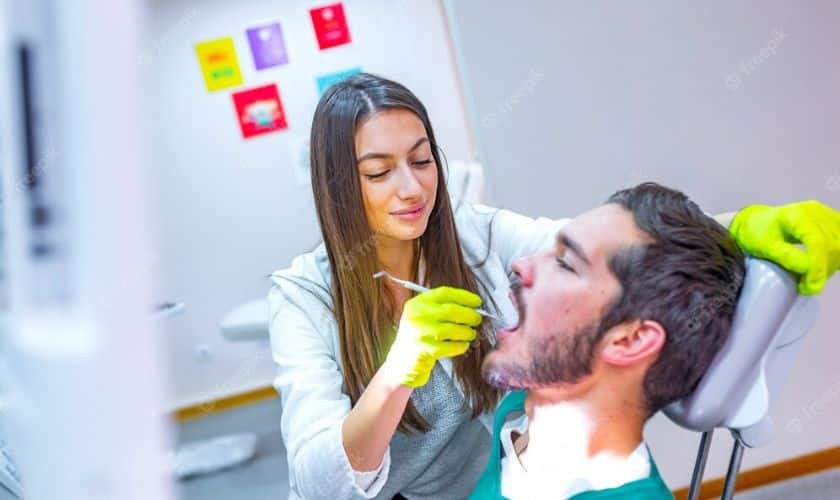 Scaling And Root Planing Female dentist examining male patient's teeth during dental procedure in office.