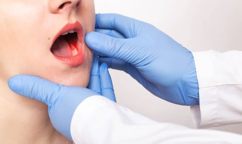Dentist examining patient's mouth and jaw during oral examination for dental implant assessment.