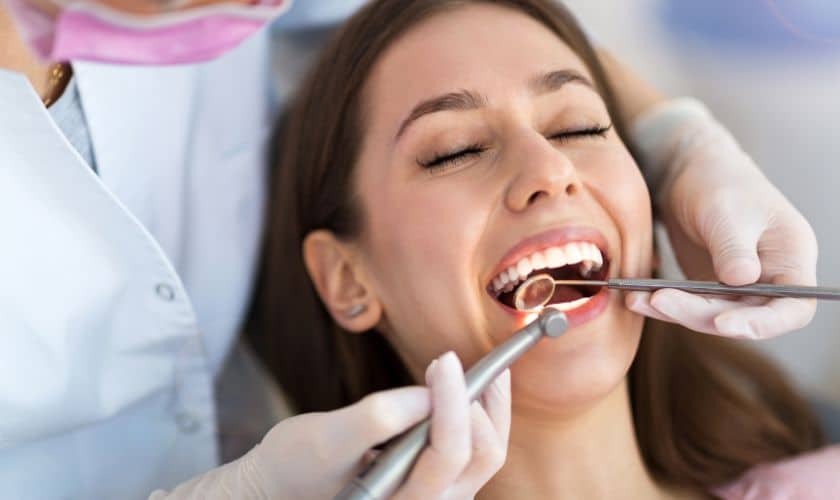 Bone Grafting in Phoenix (1) Dentist examining patient's teeth during oral examination in Phoenix dental office.