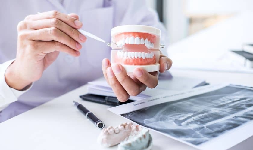 Bone Grafting in Phoenix (1) Dentist examining dental models and X-rays to explain bone grafting procedure outcomes.