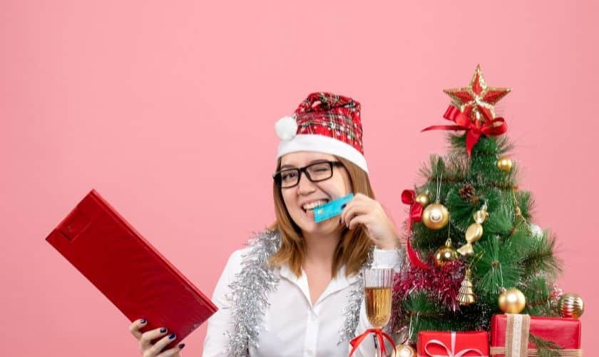 Happy woman in holiday attire holding toothbrush and gift, promoting dental care for a healthy smile.