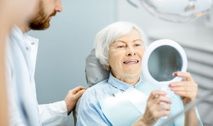 Senior patient admiring her new smile with dentist in Phoenix dental office.
