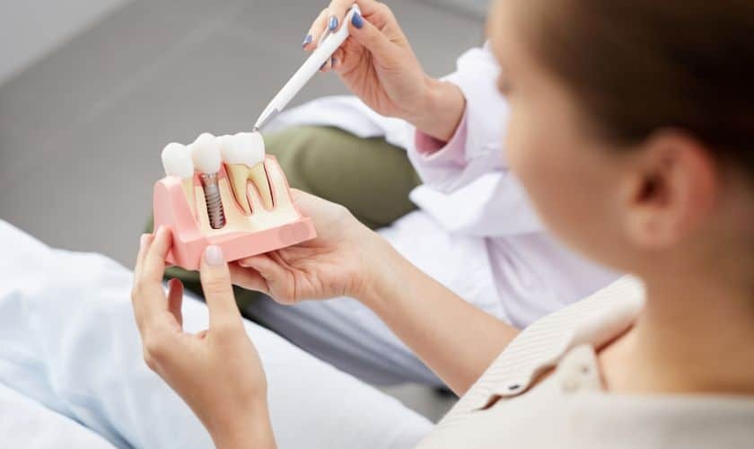 Dentist showing dental implant model to patient during consultation in Phoenix.