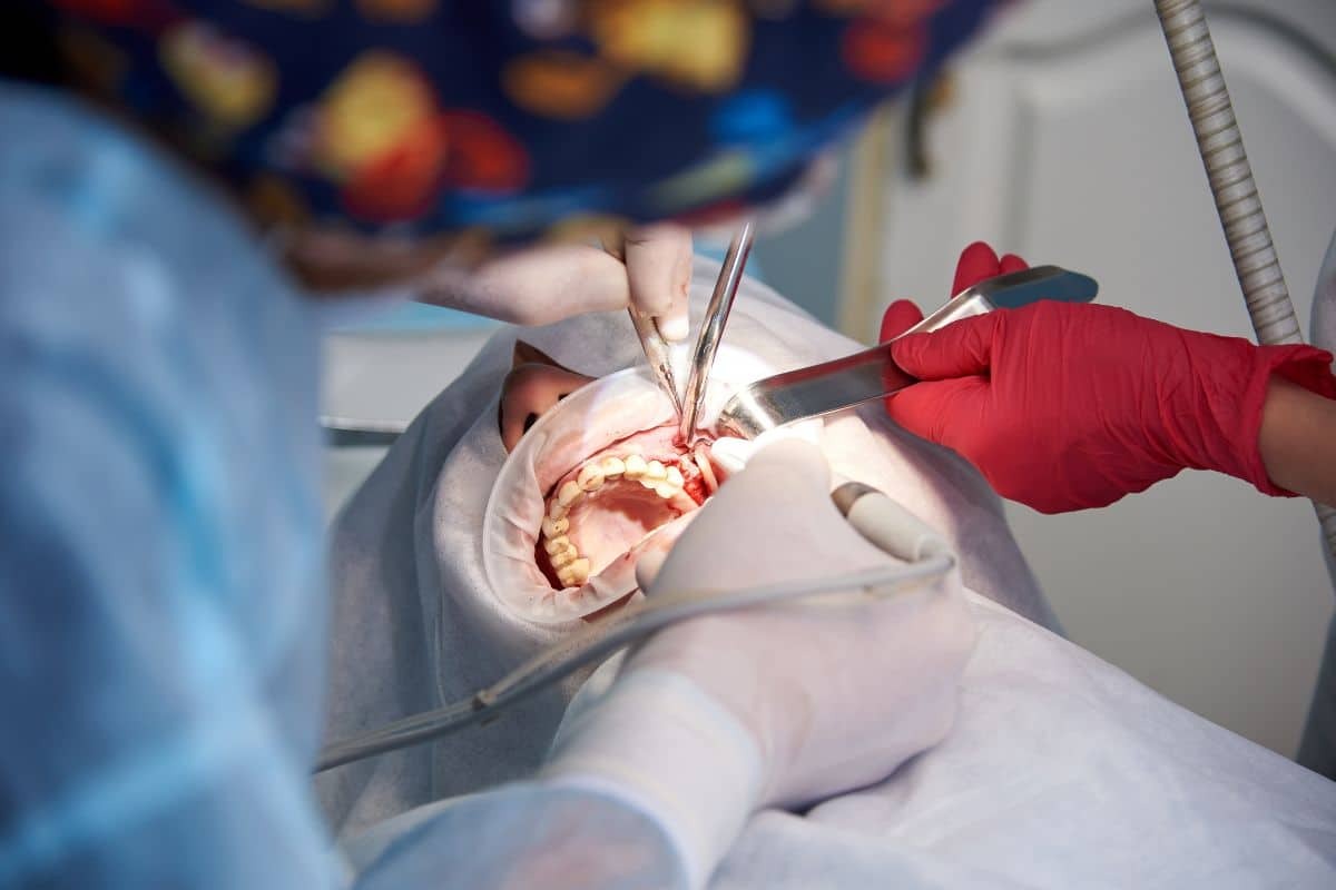 Dentist performing osseous surgery on patient's gum tissue during periodontal treatment.