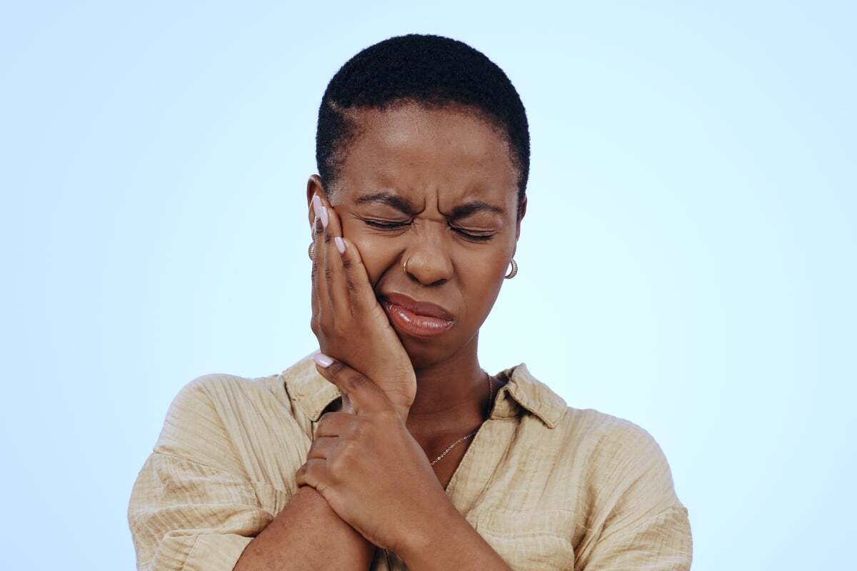 Plaque and tartar are the leading causes of gum disease Woman holding her cheek in pain, illustrating gum disease symptoms and the importance of preventive dental care.