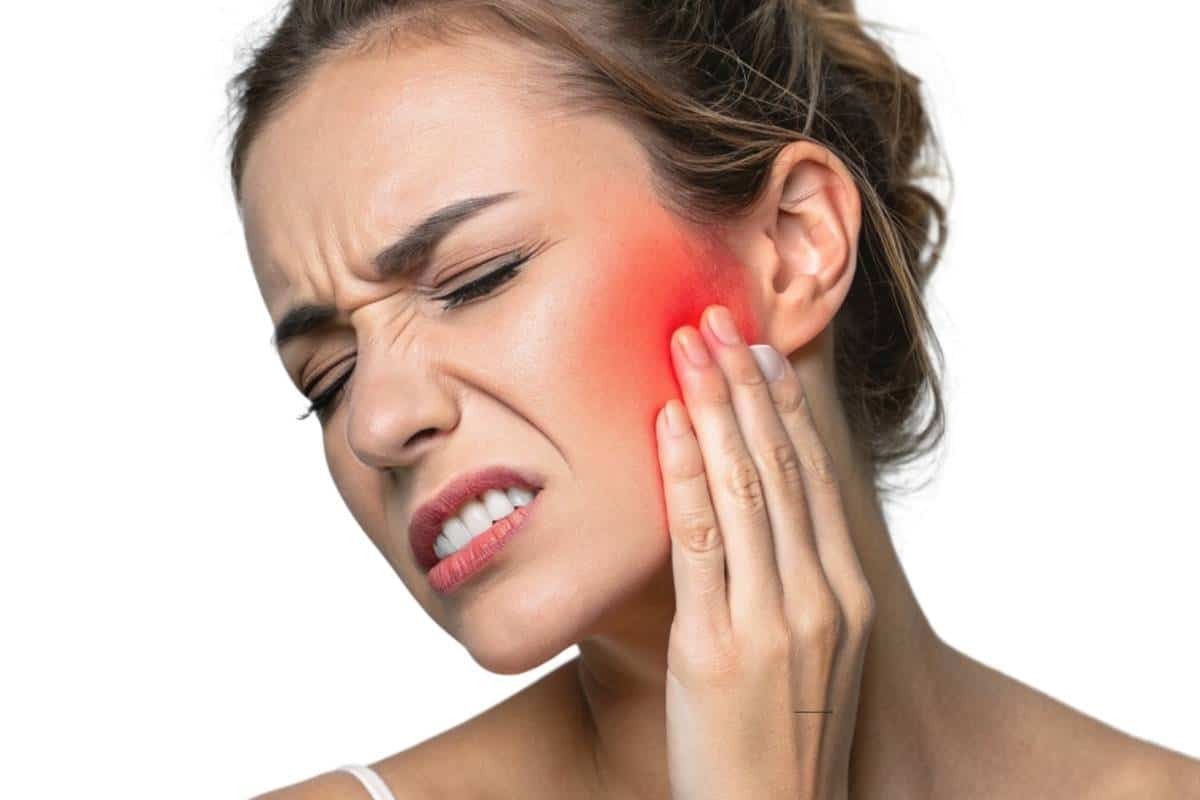 Facial Swelling from Tooth Infection Woman experiencing jaw and facial swelling from a dental infection, holding her cheek in pain.