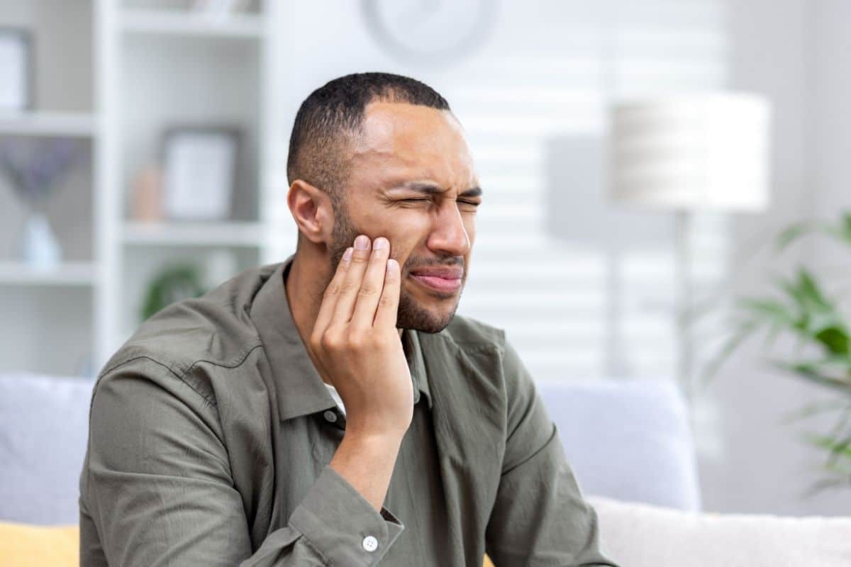 Man holding his cheek in discomfort, illustrating sinus bone graft concerns and allergy symptoms.
