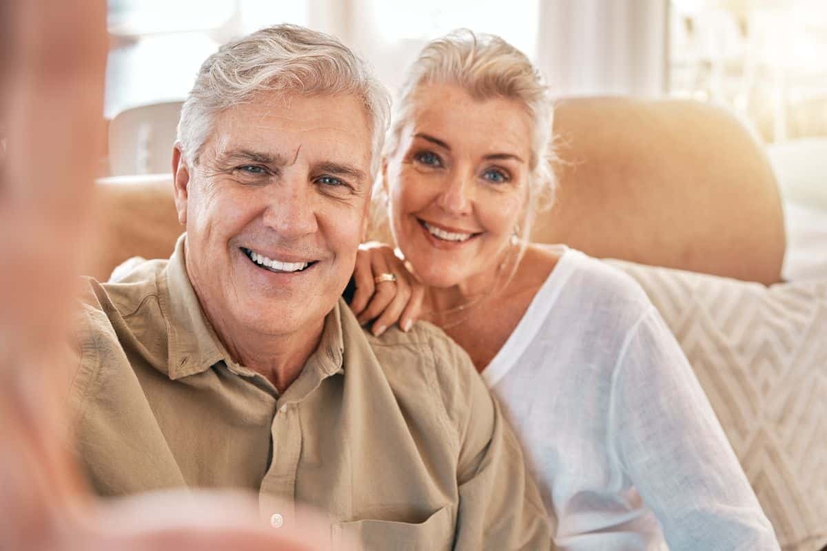 Happy senior couple smiling together in dental office setting.